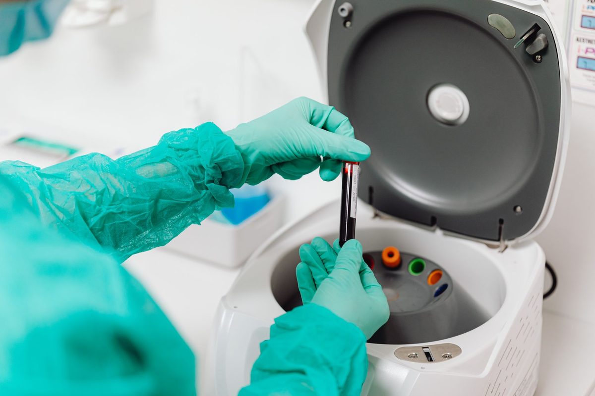 Técnica con guantes colocando tubos de muestra en una centrífuga