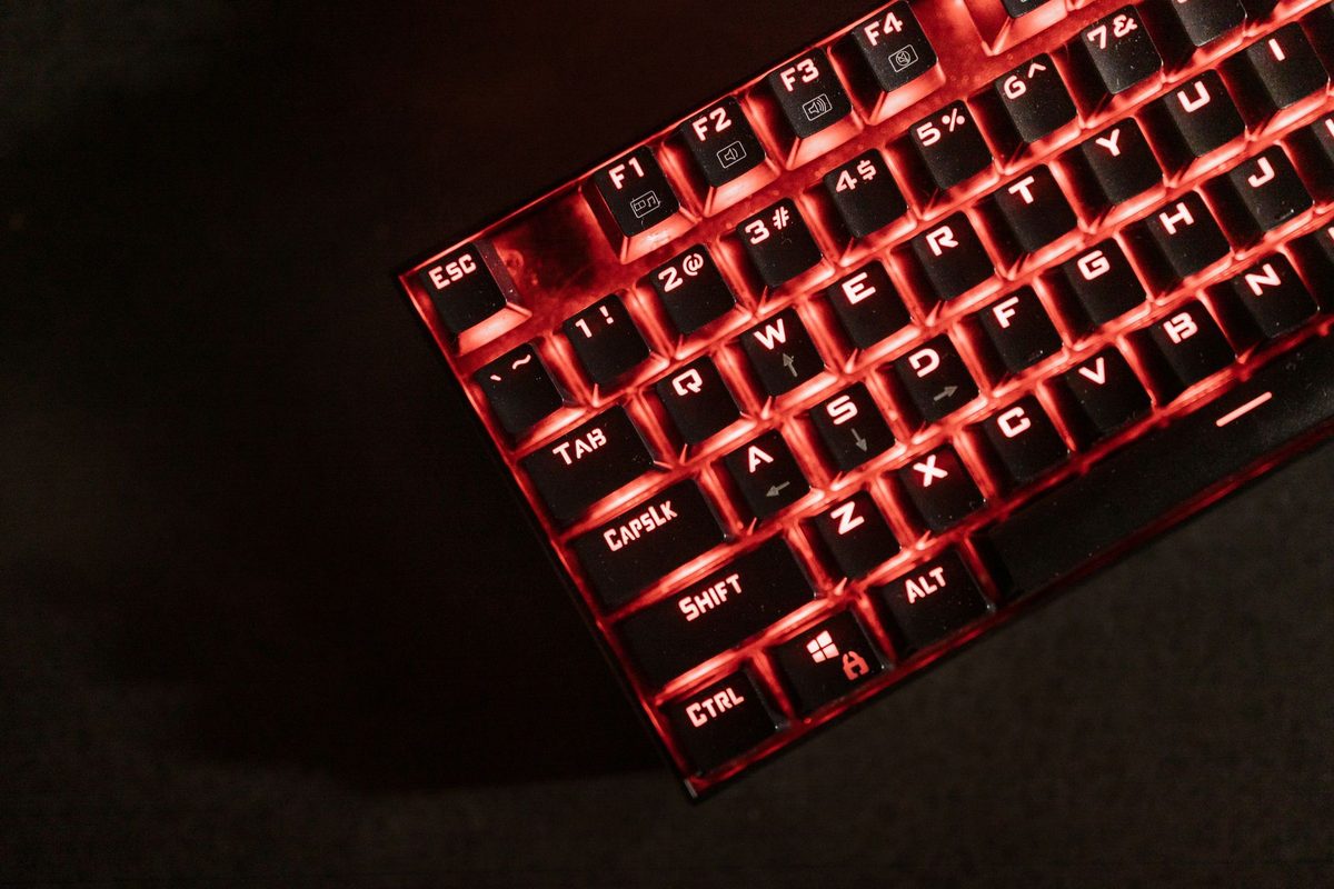 Teclado mecánico con luz roja sobre un escritorio oscuro