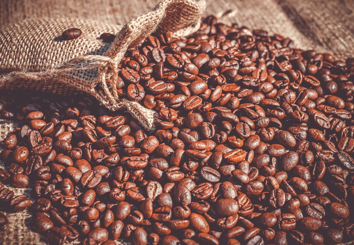 Café tostado oscuro saliendo de un saco de yute