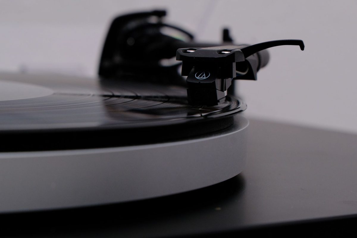 Tocadiscos gris con un vinilo negro sonando