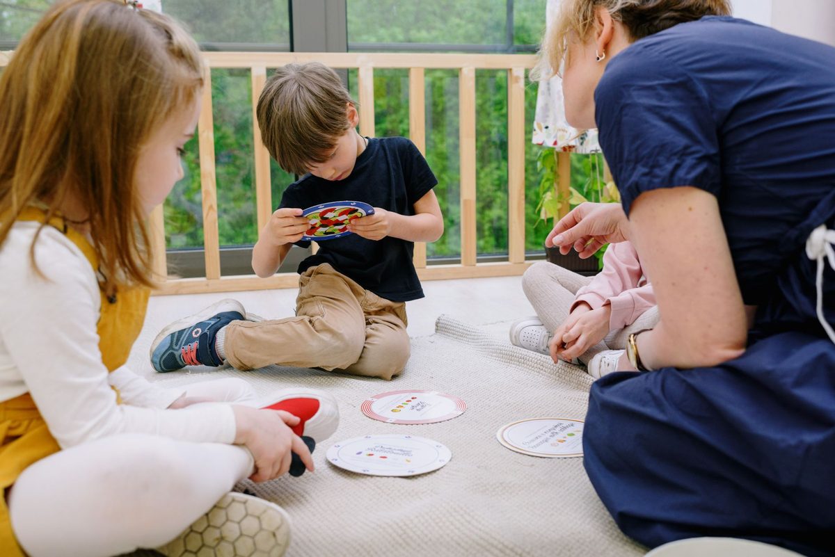 Grupo de niños pequeños jugando en el piso con una maestra