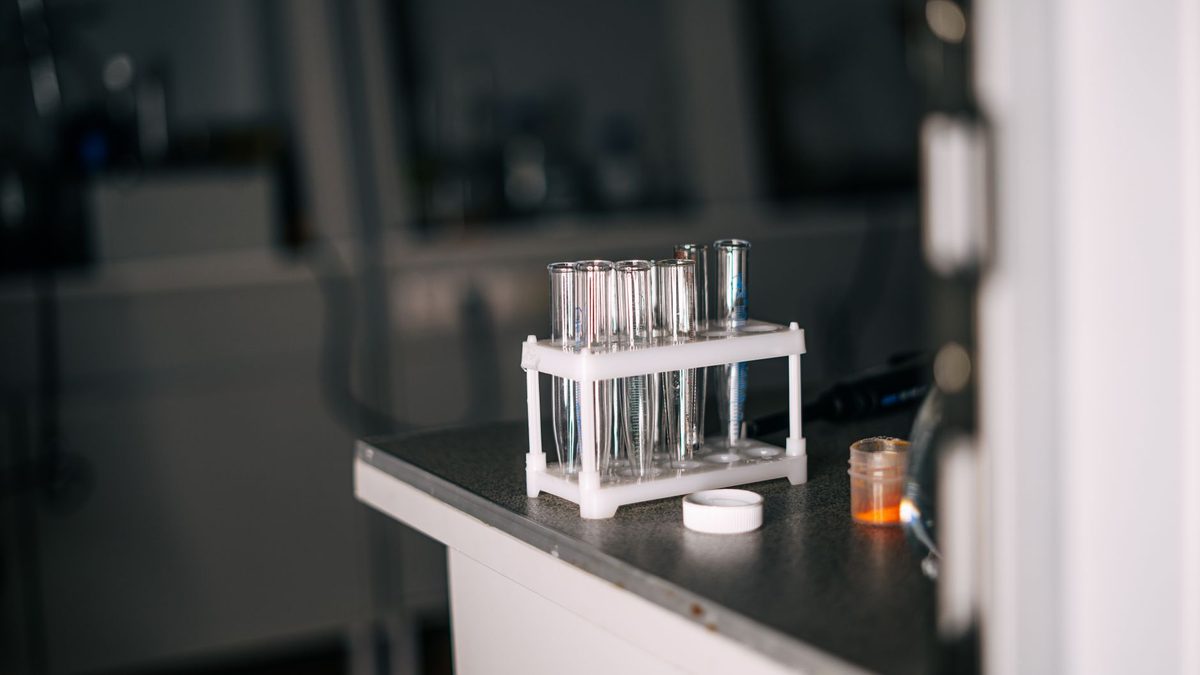 Gradilla con tubos de ensayo sobre una mesa de laboratorio en penumbra