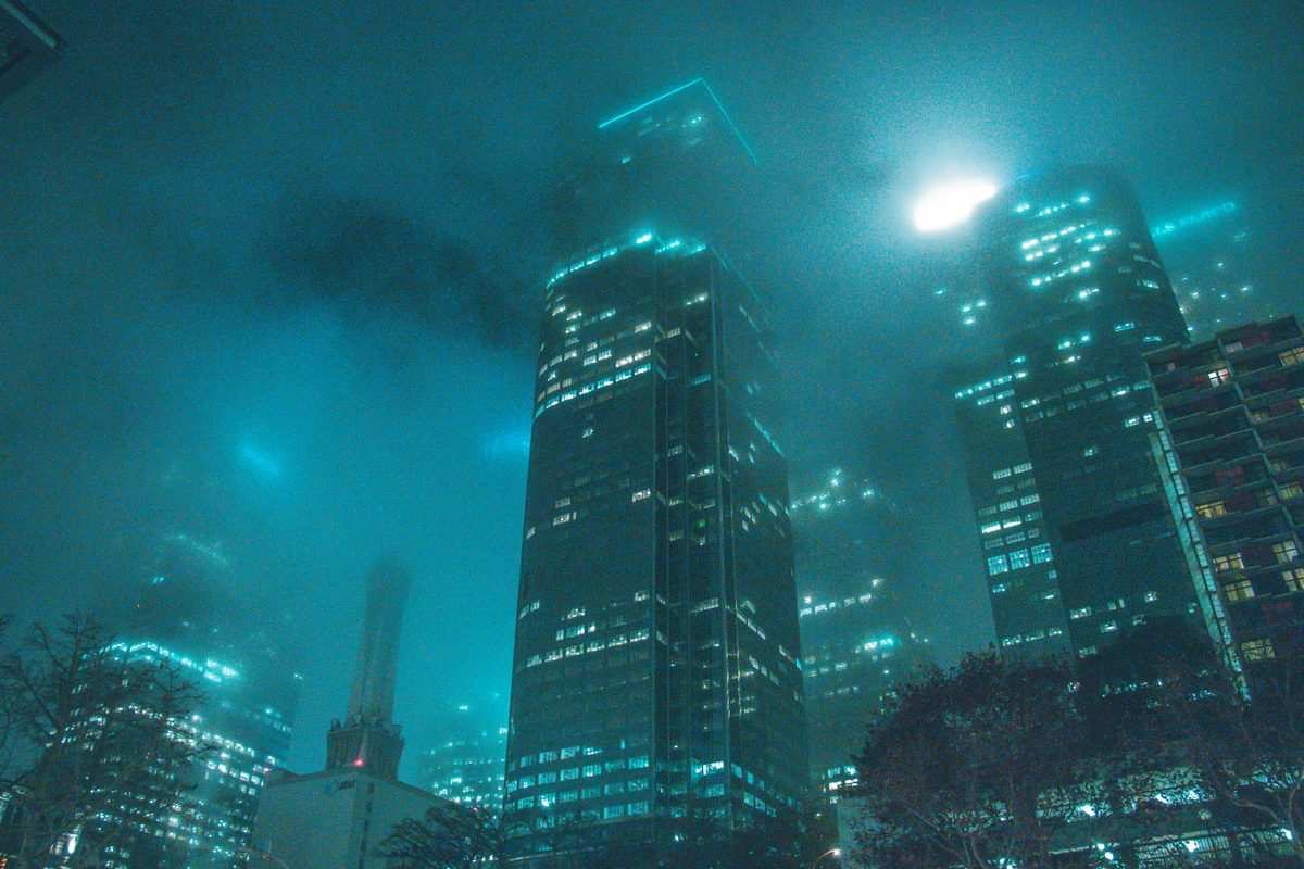 Torres de oficinas entre niebla con luz turquesa