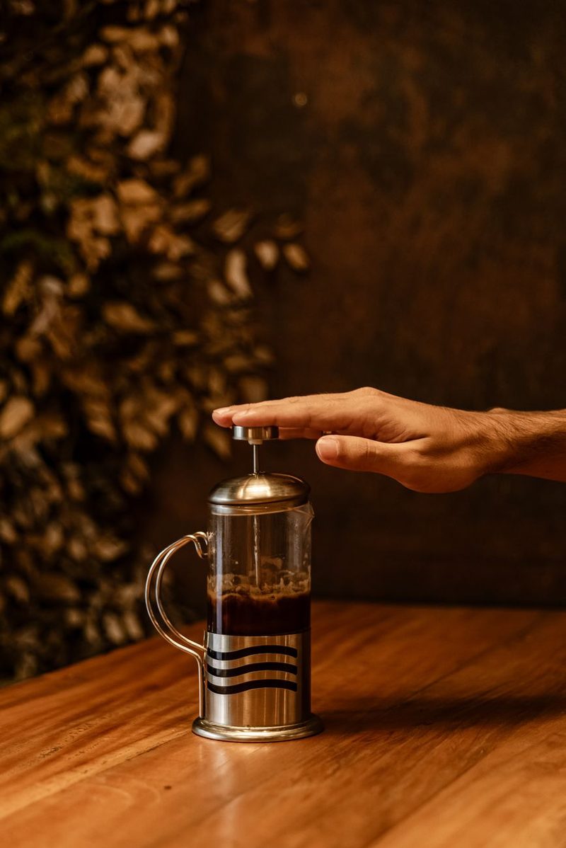 Prensa francesa con café recién preparado sobre una mesa de madera