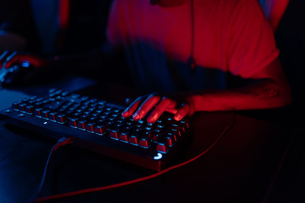 Manos escribiendo en un teclado iluminado en rojo