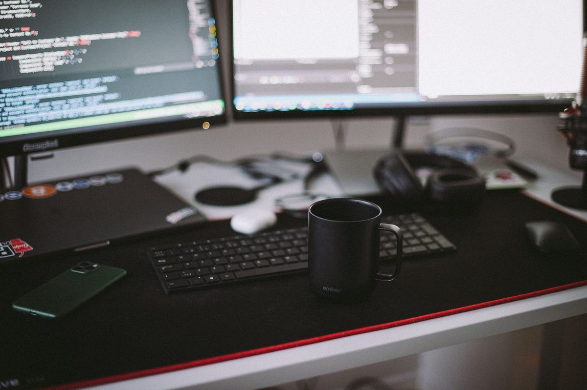 Desarrollador front-end trabajando en su escritorio frente a una laptop con líneas de código y una interfaz en pantalla